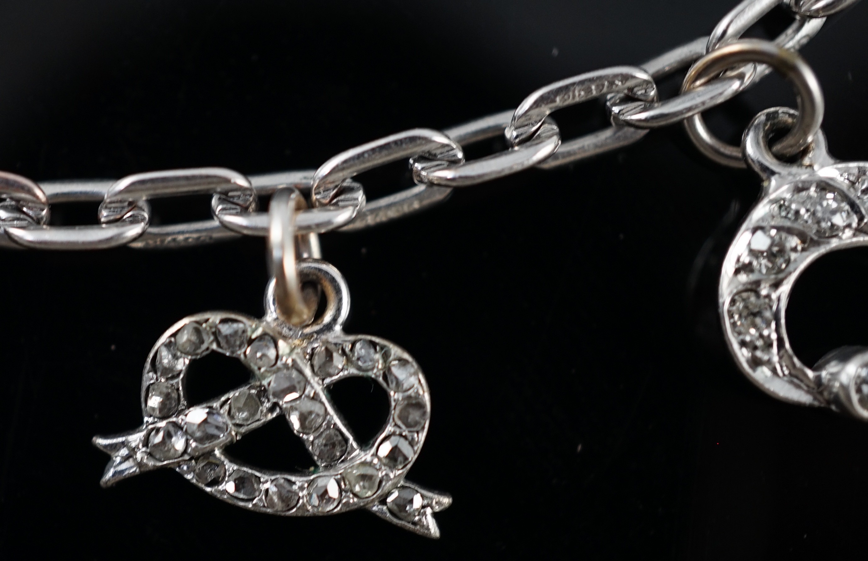 A 9ct white gold charm bracelet, with French platinum and diamond set clasp and hung with nine assorted charms, eight set with diamonds